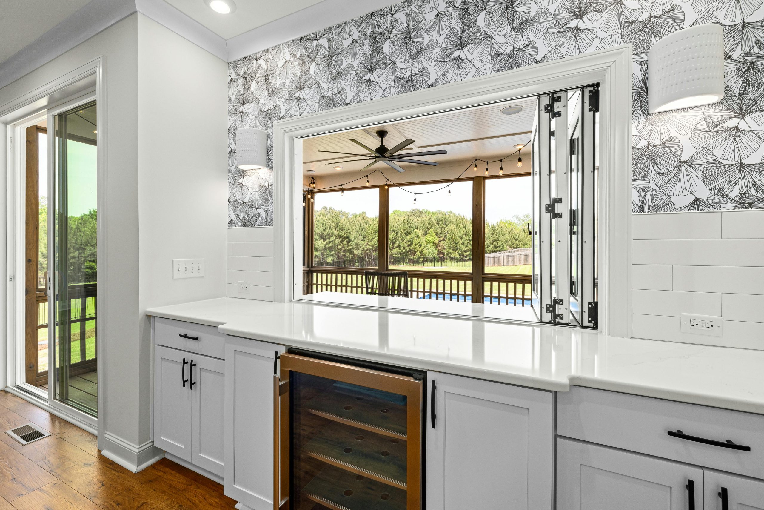 Elegant modern kitchen interior featuring a countertop, wine cooler, and an open view to the outdoors through large patio doors.